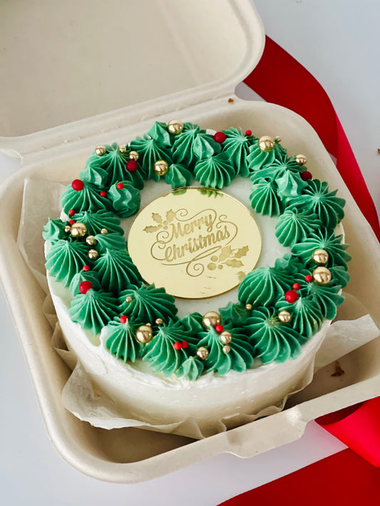 mini cake with wreath piped and Merry Christmas in the middle