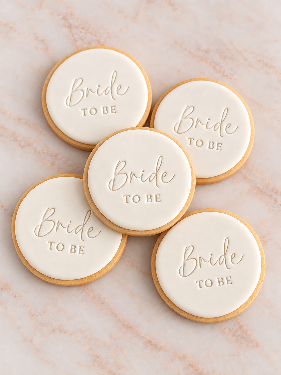 Five round fondant cookies with 'Bride TO BE' stamped in elegant script