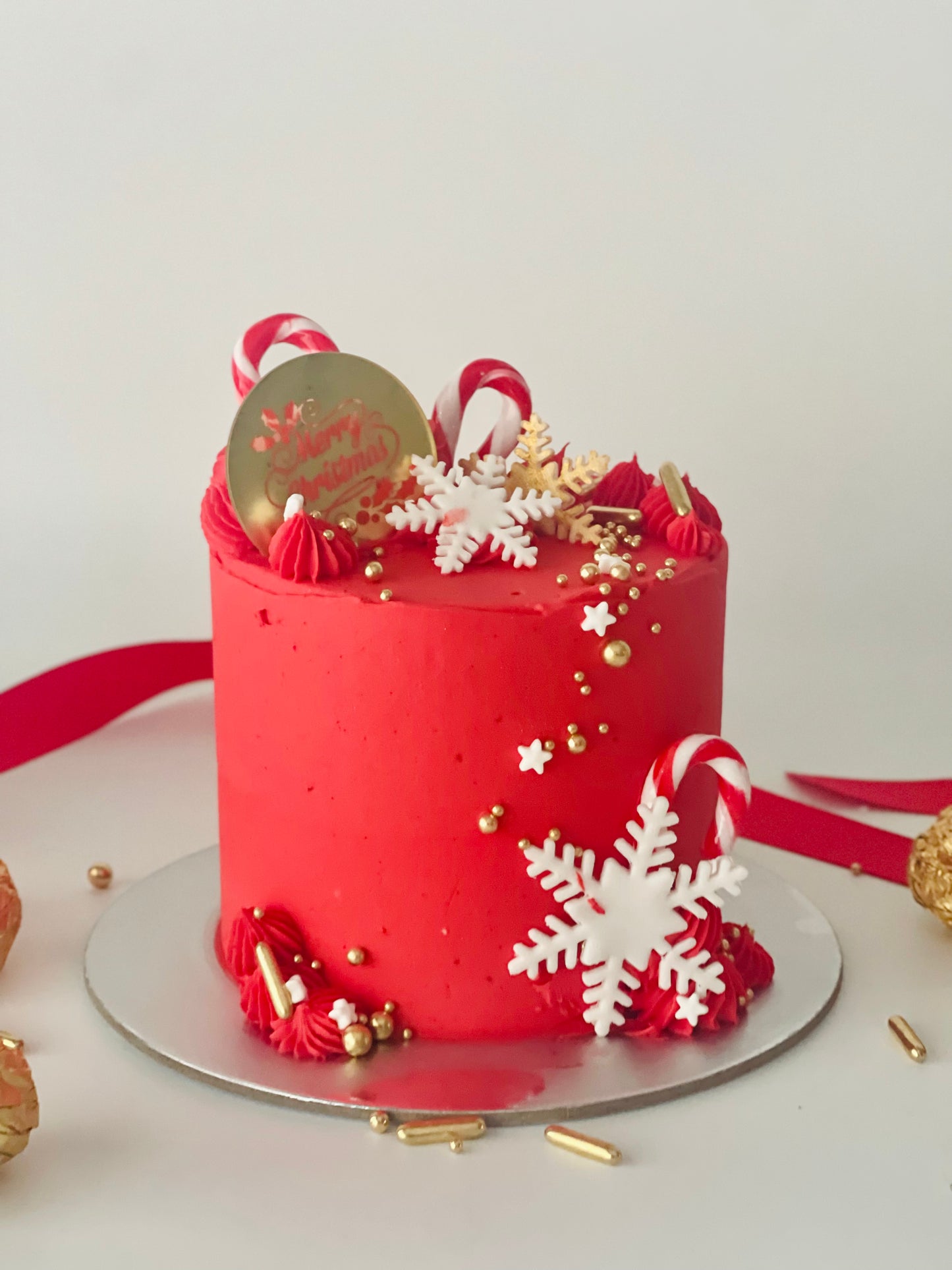 red cake with icicles & merry Christmas. Finished with gold sprinkles & candy canes