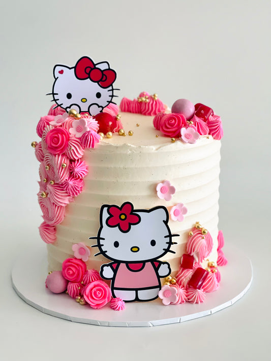 A Hello Kitty themed cake decorated with white and pink icing, and Hello Kitty character figurines on top.