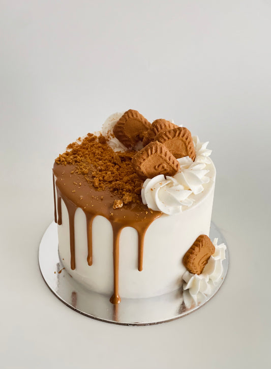 Vanilla cake with biscoff drip, swirl piping, topped with biscoff biscuits and crushed biscoff