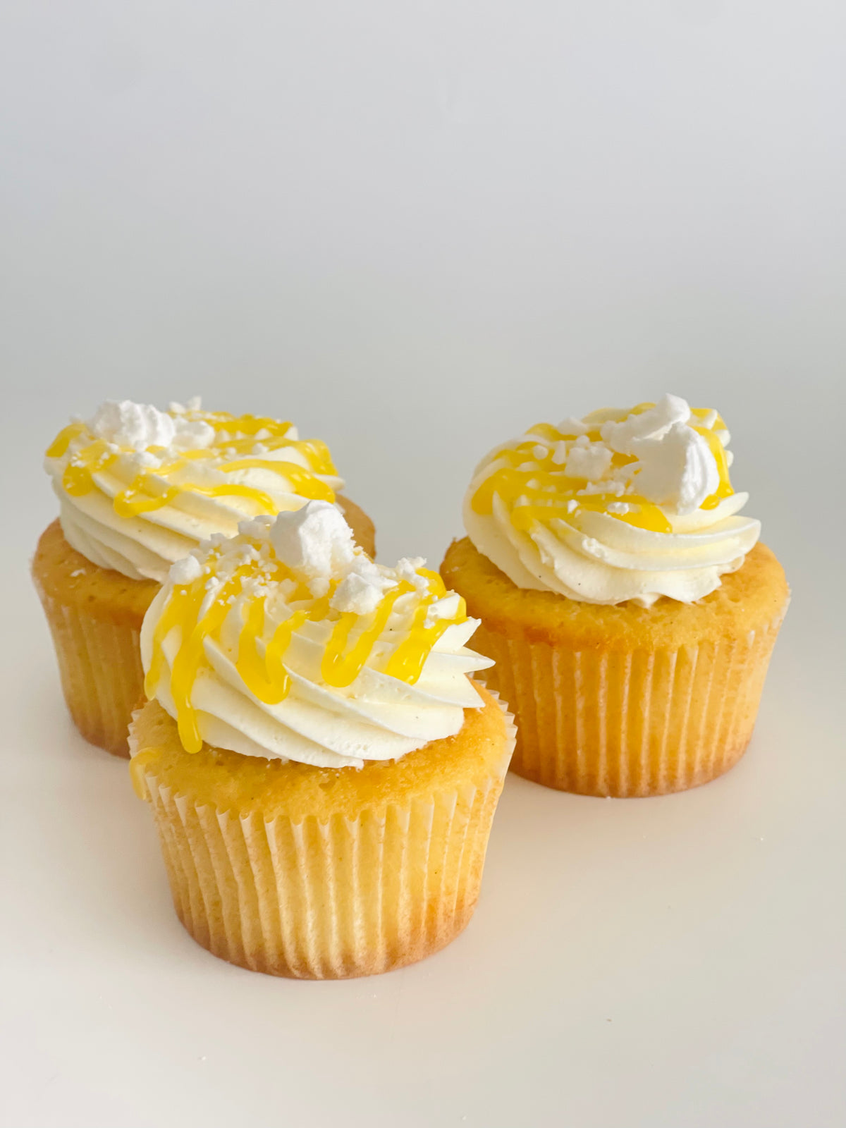 Vanilla cupcakes with lemon filling, white frosting and lemon curd drizzle 