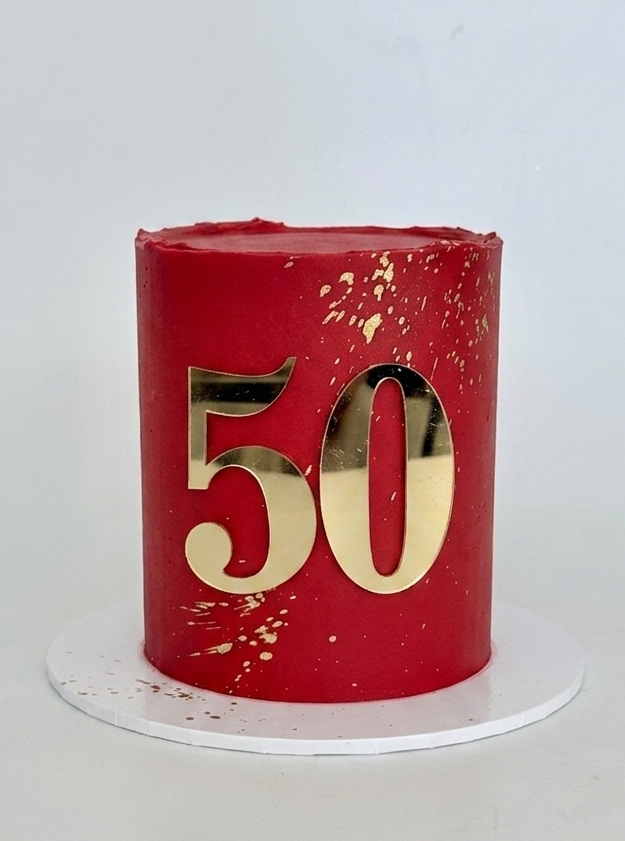 Red cake with gold number 50 and gold splatter. a stunning celebration cake