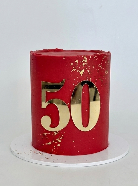 Red cake with gold number 50 and gold splatter. a stunning celebration cake