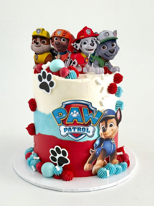Paw Patrol-themed birthday cake with character figures on a white background