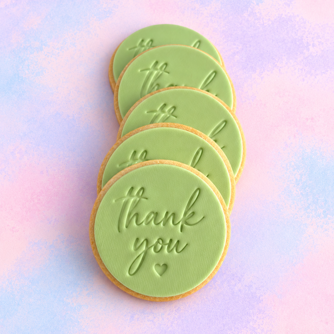 Light green decorated cookies with 'thank you' written in cursive