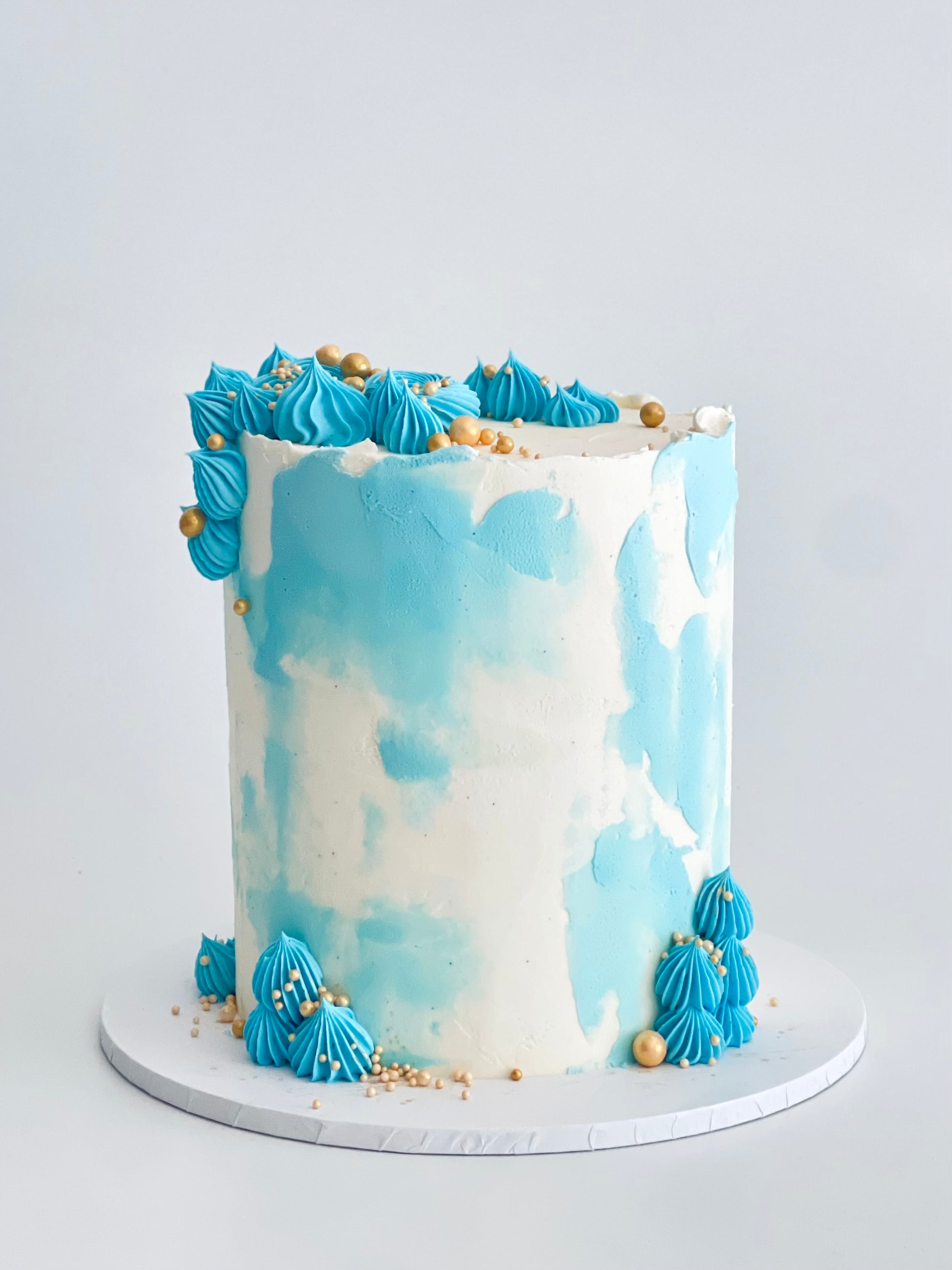 cake with blue touches and piping, finished with gold sprinkles
