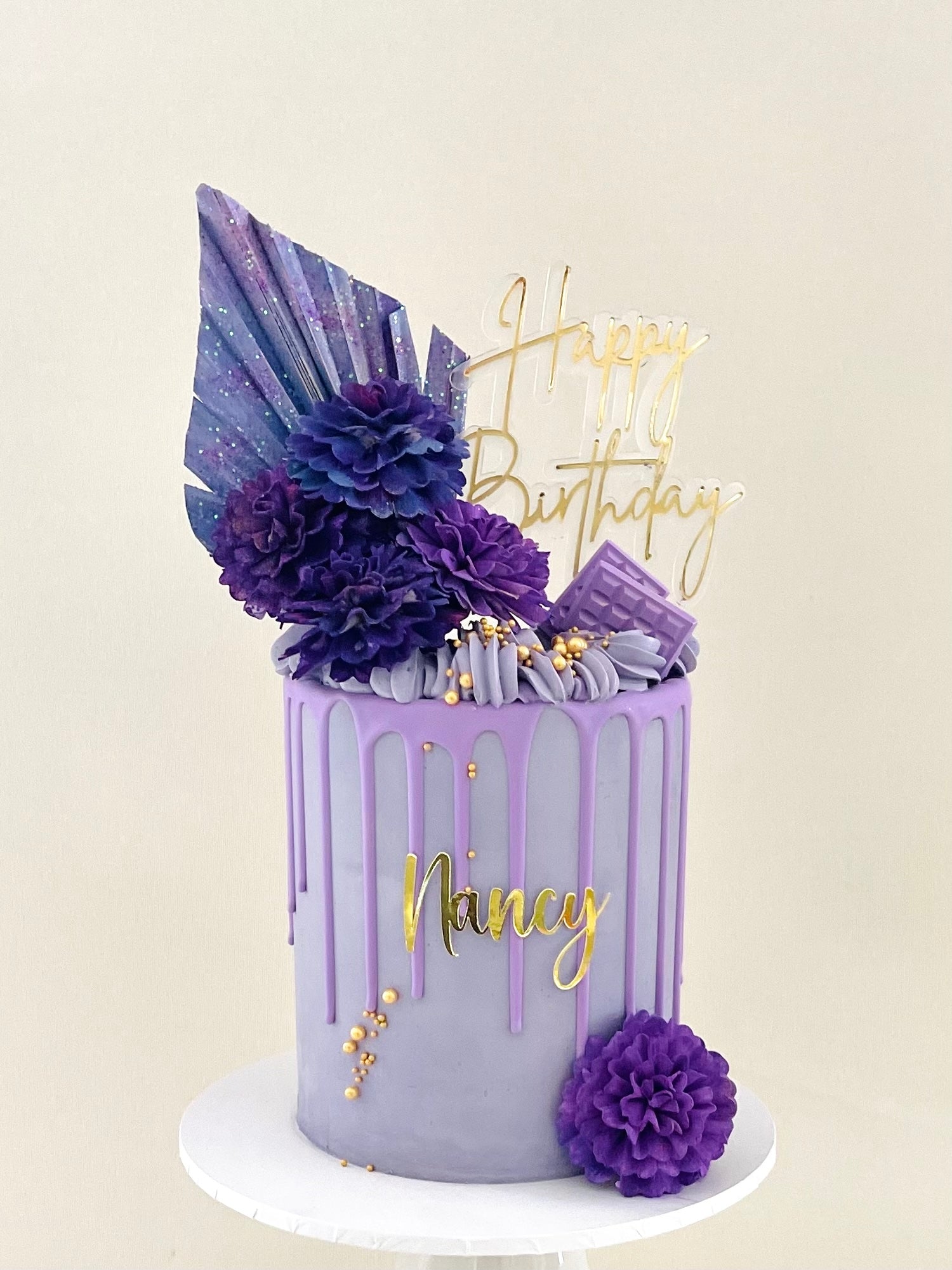 purple birthday cake with flowers, gold drip and sprinkles